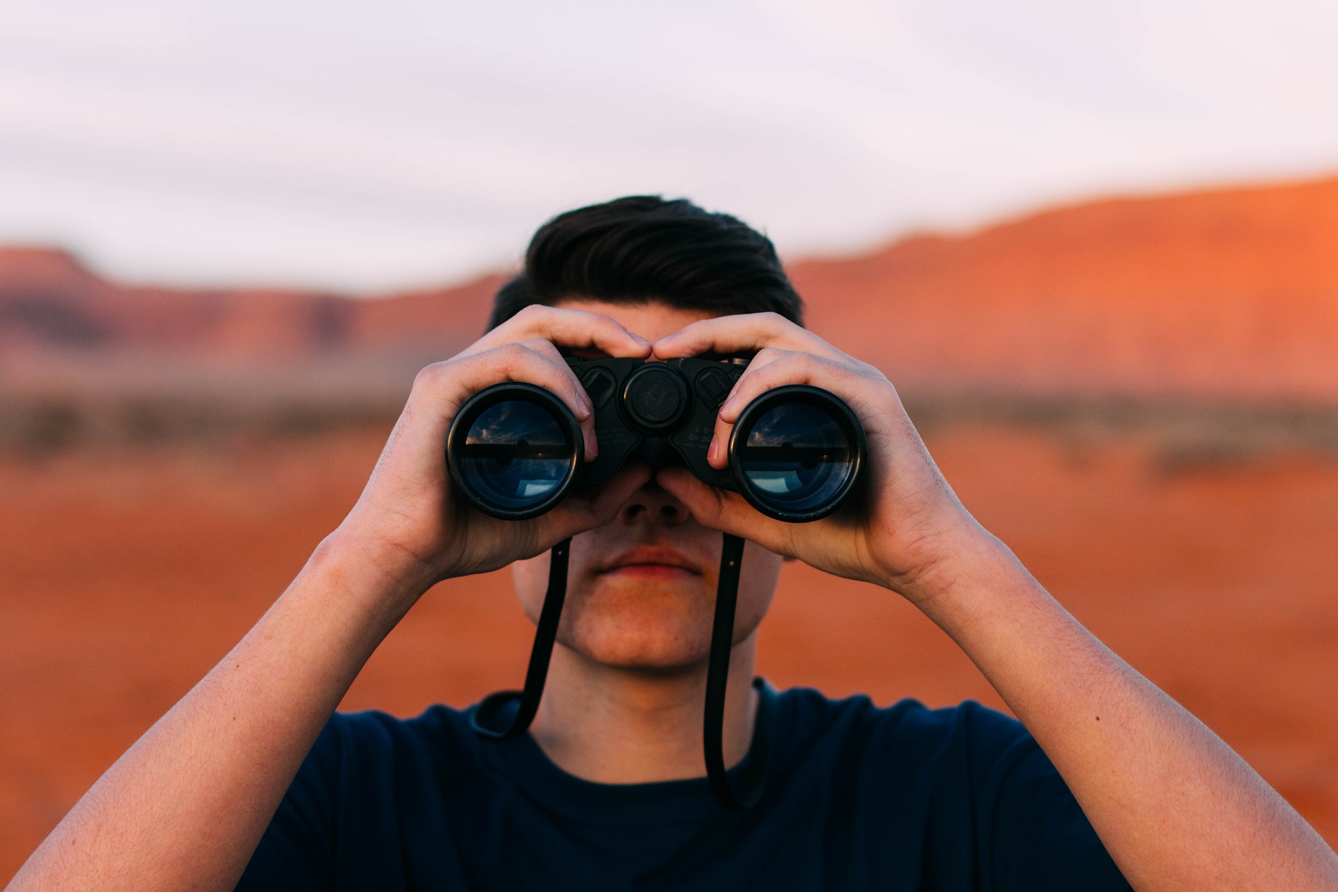 uomo che guarda col binocolo verso il futuro